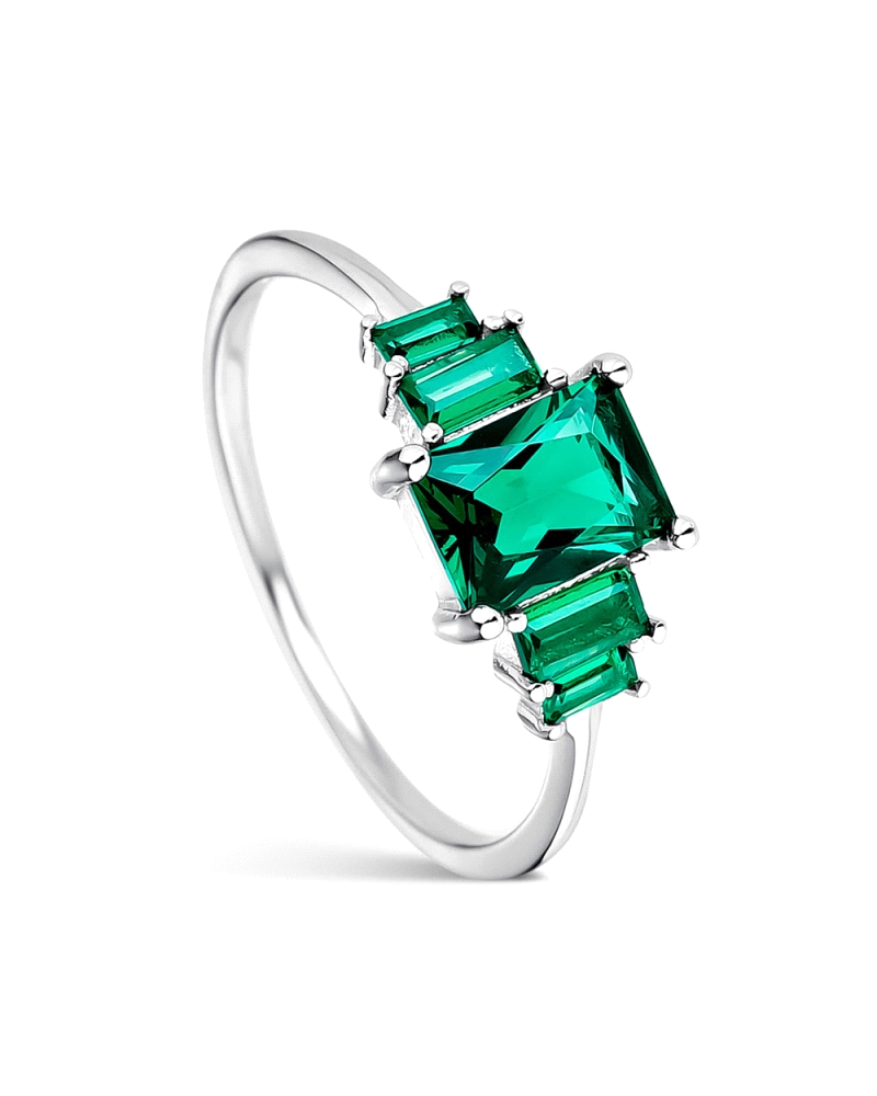 Este elegante anillo de plata rodiada presenta una brillante circonita verde en talla esmeralda, delicadamente asegurada por gar