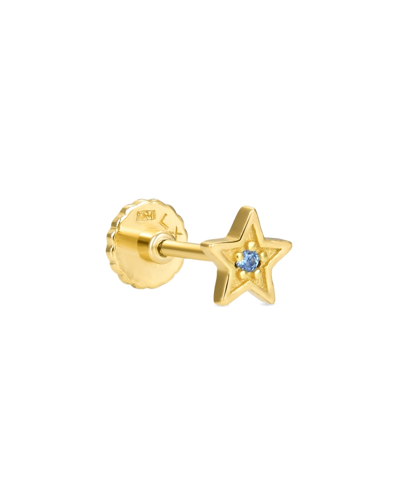 Un piercing de plata de ley bañado en oro amarillo, con forma de estrella y una circonita central azul. Este diseño combina el l