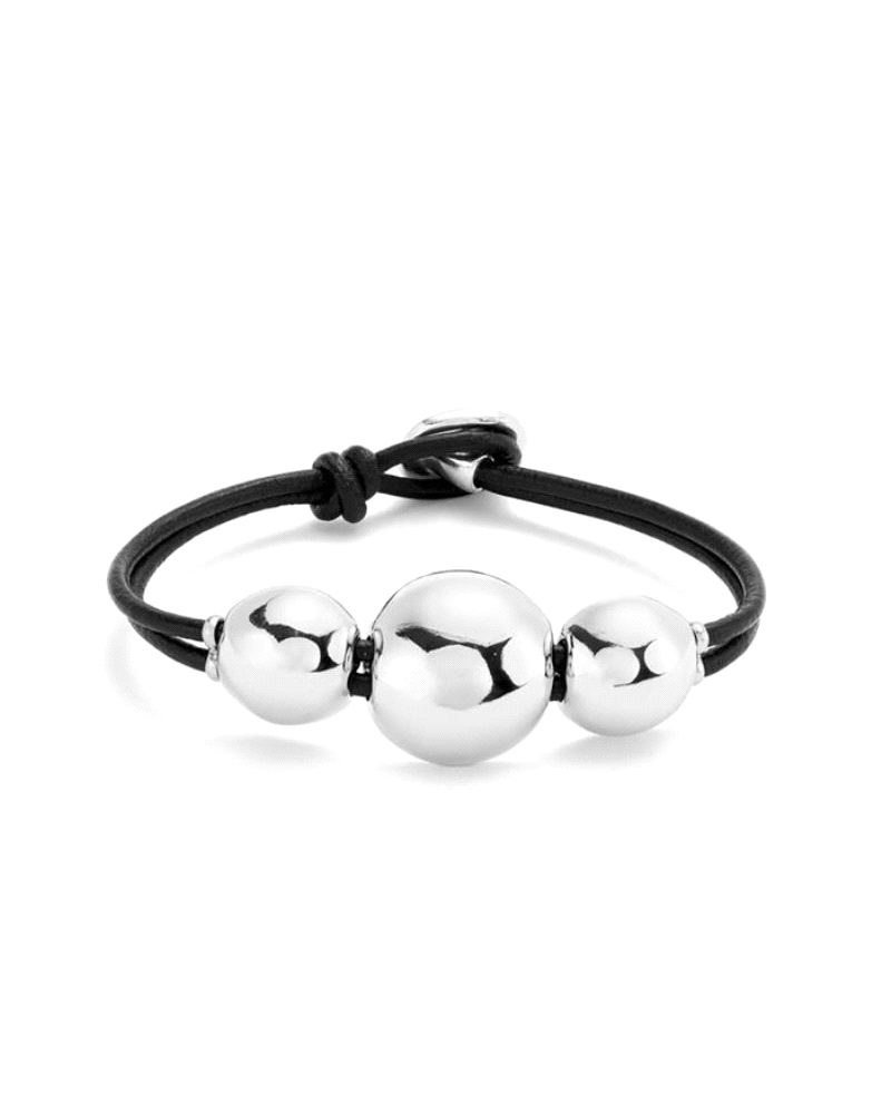 Esta pulsera con cordón negro combina tres bolas bañadas en plata de diferentes tamaños en una composición que juega con el volu