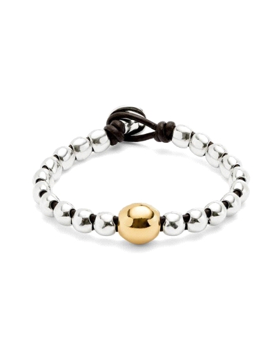Esta pulsera combina cuentas redondeadas bañadas en plata con una bola central bañada en oro, en un diseño elástico con cierre d