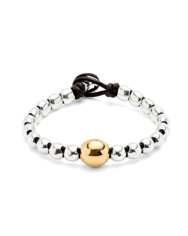Esta pulsera combina cuentas redondeadas bañadas en plata con una bola central bañada en oro, en un diseño elástico con cierre d